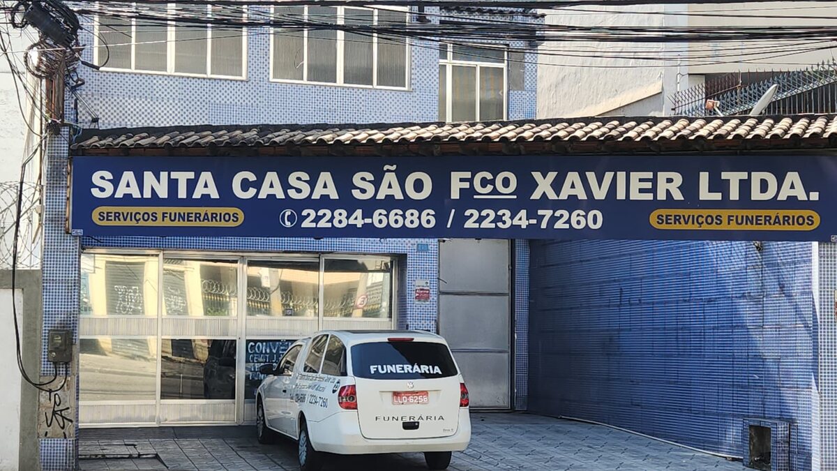 Fachada da Santa Casa São Francisco Xavier, com placa azul escrita “Santa Casa São Fco Xavier Ltda. — Serviços Funerários” e os telefones 2284-6686 e 2234-7260, na Rua São Francisco Xavier, 418, no Maracanã.